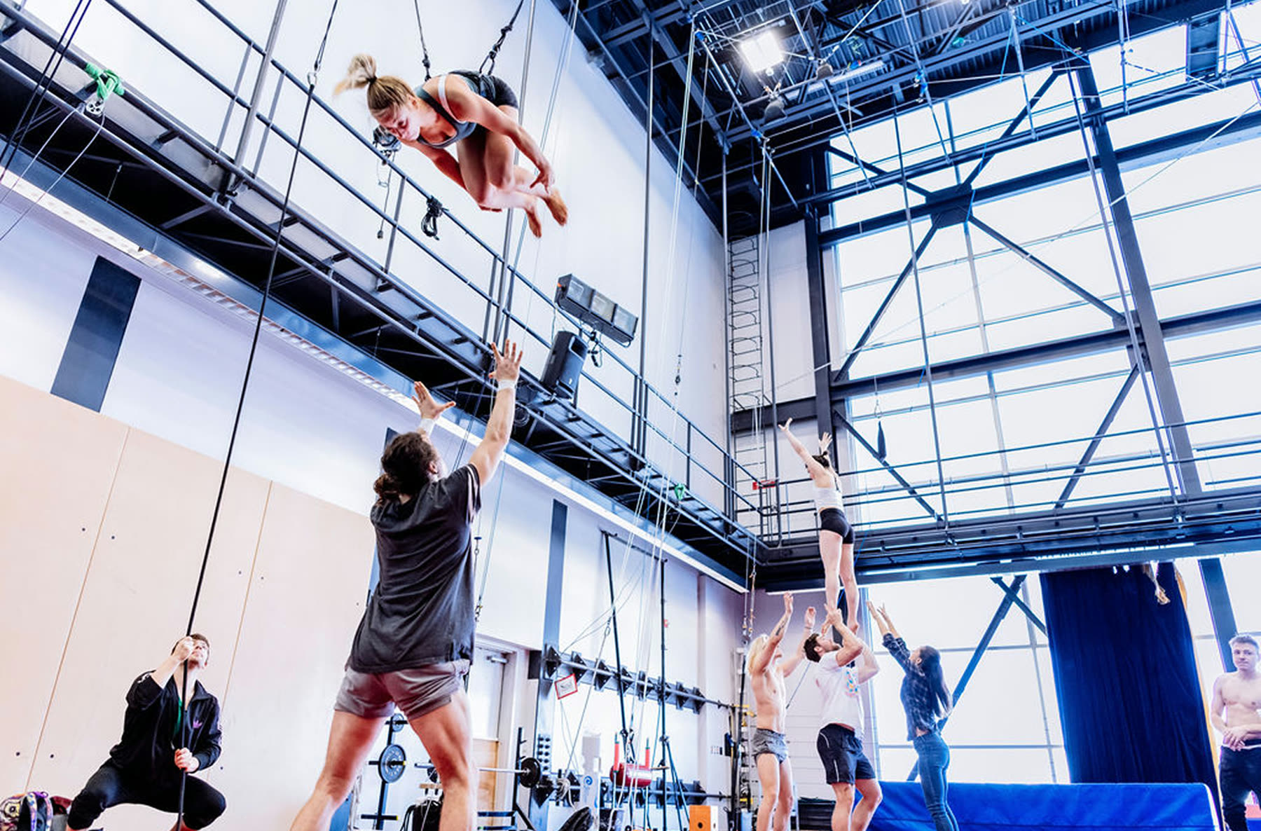 Une voltigeuse en suspension au-dessus de son porteur, dans la salle d’entraînement