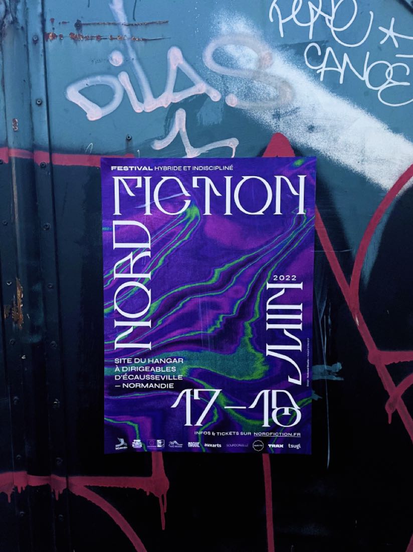 L’affiche collée sur un rideau de fer taggé, de nuit
