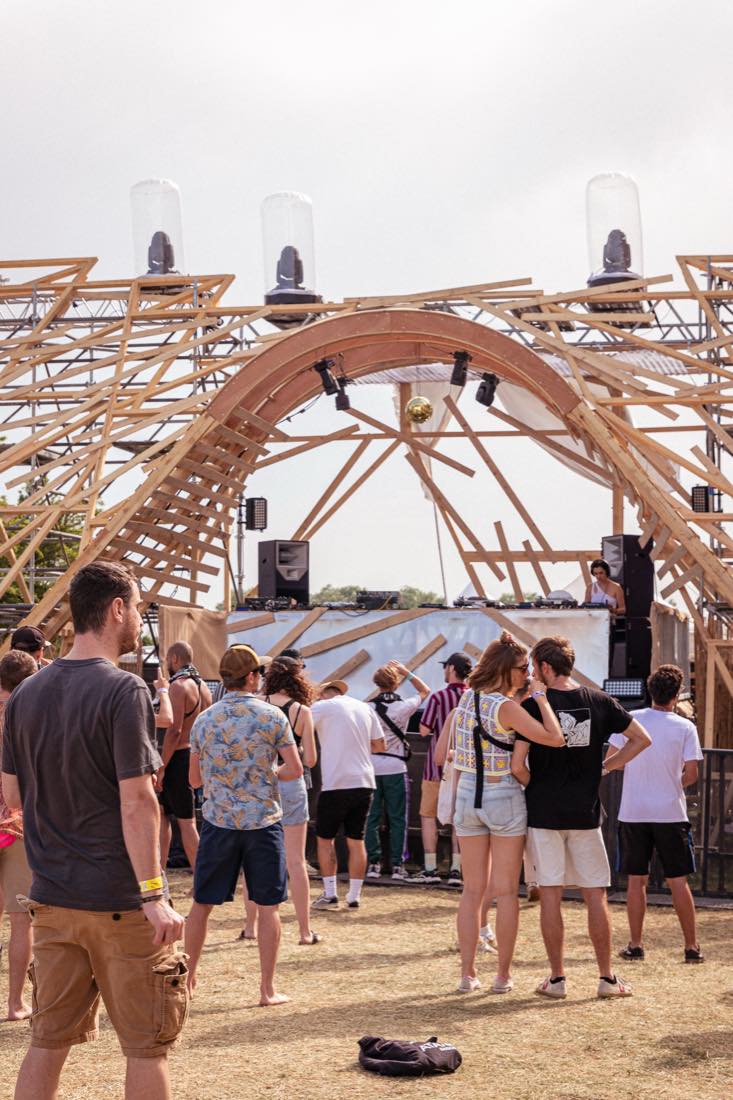 Une arche de bois montée sur le site, des festivaliers qui passent dessous
